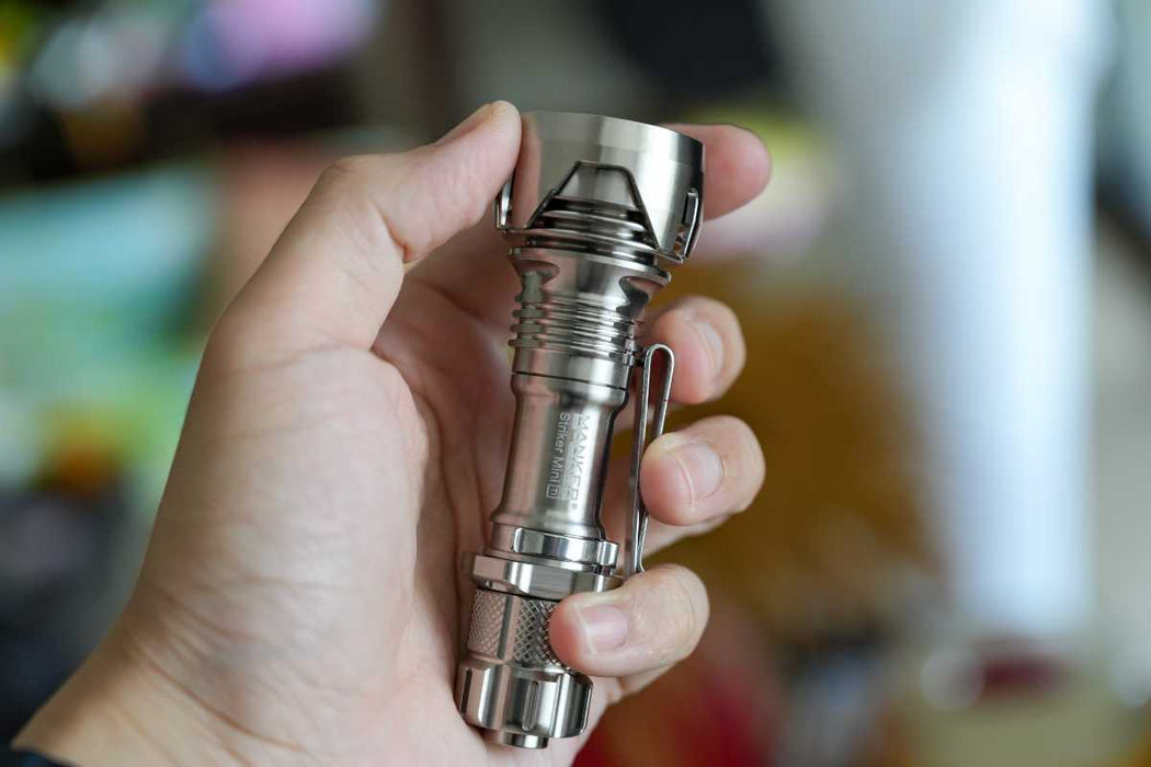 A person holding a Manker Striker Mini Titanium EDC Flashlight in their hand.