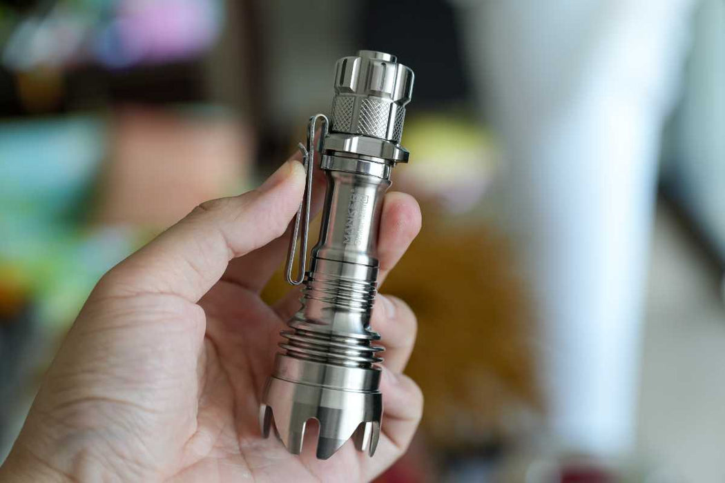 A person holding a Manker Striker Mini Titanium EDC Flashlight in their hand.