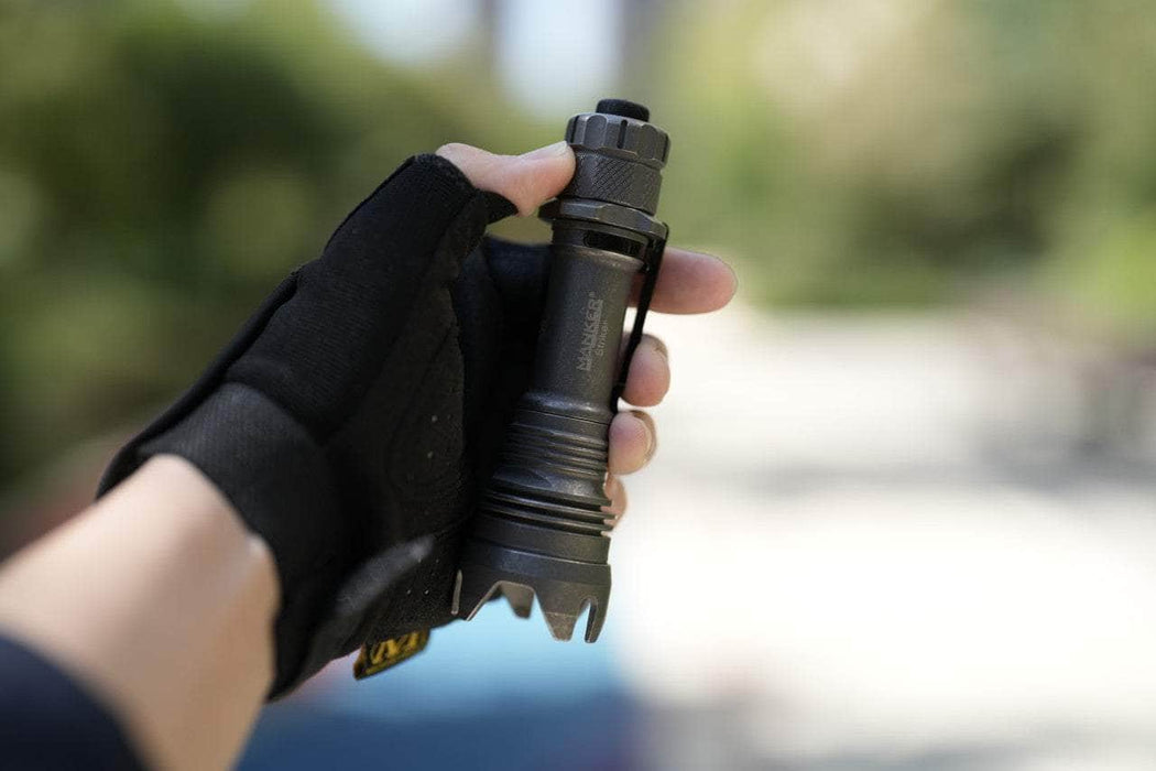 A person holding a Manker Striker Titanium flashlight in their hand.
