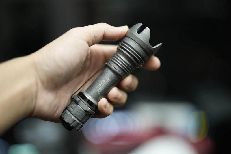 A person holding a Manker Striker Titanium flashlight in their hand.