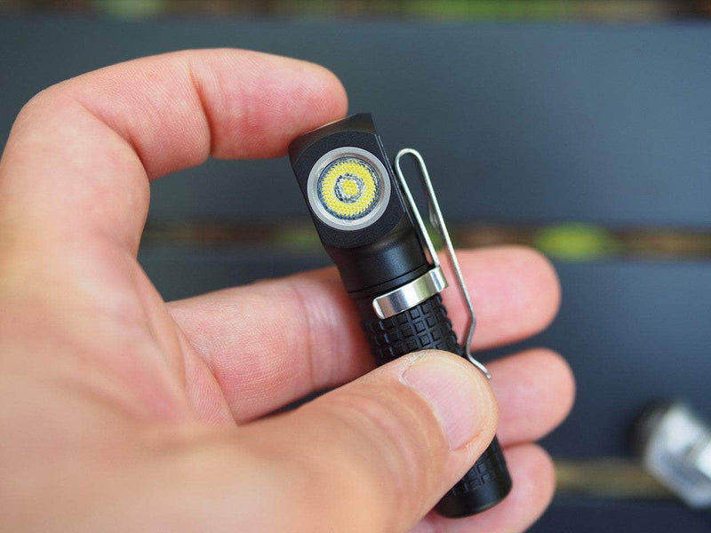 A hand holds the Manker E02 III AAA / 10440 Flashlight, a compact black flashlight that features a high-performance LED bulb delivering 560 lumens of illumination. This flashlight, equipped with a metal clip, stands as the brightest everyday carry option for all your lighting needs.