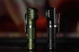 Two Manker E02 III flashlights are pictured standing upright; the left one is in green and the right one in black. Both feature textured grips and metal clips, equipped with high-performance LED technology providing 560 Lumens of illumination—ideal for bright everyday carry.