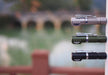 Three Manker E02 III flashlights in gray, green, and black deliver 560 Lumens of illumination with high-performance LEDs, magnetically attached to a metal surface. A blurred bridge and water provide a serene backdrop for these brightest everyday carry essentials.