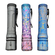Three flashlights with clips, including a ReyLight Anodized Ti LAN, stand upright. They feature designs in gray, floral-patterned purple, and circuit board blue. Each one uses the Nichia 519A Hi-CRI LED for outstanding illumination.