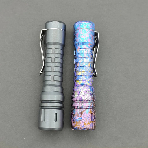 A pair of tactical flashlights include a matte black one with segmented grip and the ReyLight Anodized Ti LANapple, which flaunts a bright, textured splatter design. Both have belt clips and utilize an XPL HI 6000K LED for maximum brightness.