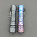 A pair of tactical flashlights include a matte black one with segmented grip and the ReyLight Anodized Ti LANapple, which flaunts a bright, textured splatter design. Both have belt clips and utilize an XPL HI 6000K LED for maximum brightness.