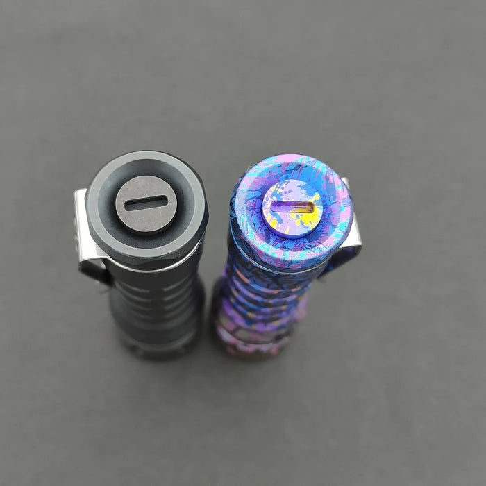 Two flashlights viewed from above on a gray background: one is classic metallic gray titanium, and the other is a ReyLight Anodized Ti LANapple with a multicolored speckled design. Both feature XPL HI 6000K LEDs for superior illumination.