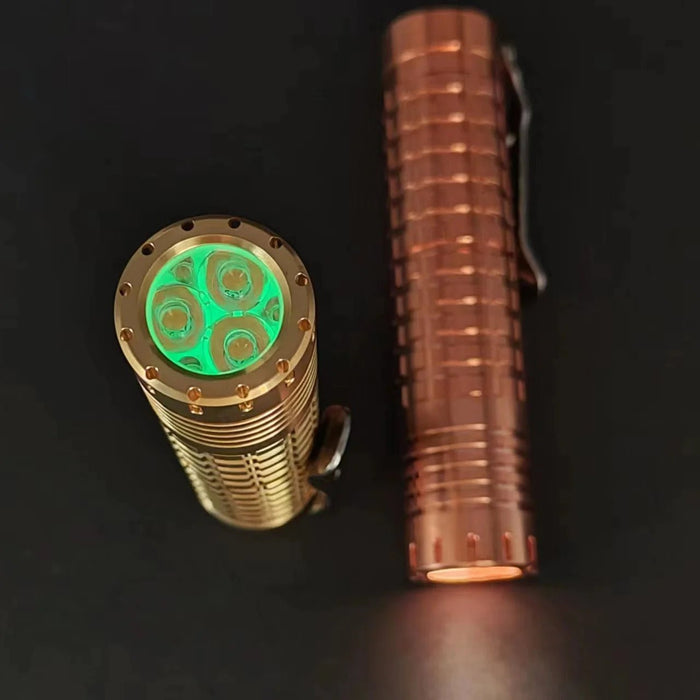 A green led flashlight next to a ReyLight Dawn - Copper.