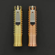 Two different colored ReyLight Dawn - Copper lighters on a black surface.