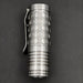 The ReyLight Dawn Hex - Ti is a compact metal flashlight with a hexagonal honeycomb pattern, pocket clip, grooved rings near the base, and Nichia 519a LED, powered by an 18350 Li-ion battery for long-lasting performance.
