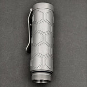 A ReyLight Dawn Hex - Ti flashlight featuring a hexagonal patterned grip, pocket clip, and Nichia 519a LED is displayed against a plain dark background.