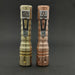Two metallic flashlights, a ReyLight LANapple in copper and one in bronze, stand upright on a dark surface. They feature textured grips and flower-engraved clips. The copper flashlight gleams with the brilliance of a CREE XPL-HI 6000K LED.