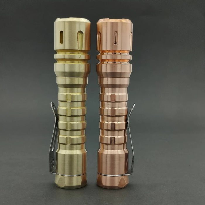 Two Reylight LANapple - Copper flashlights on a black surface.