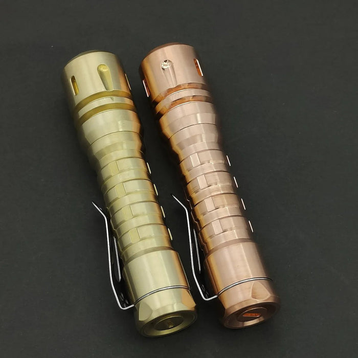 Two different colored Reylight LANapple - Copper flashlights on a black surface.