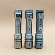Three ReyLight LANapple - Ti flashlights with pocket clips stand upright on a plain, light brown surface against a neutral background; each is designed for use with a rechargeable 14500 battery.