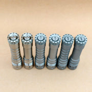 Six gray metal flashlights, including the ReyLight LANapple - Ti, are arranged upright in a row on a light brown surface. Some models support rechargeable 14500 batteries.