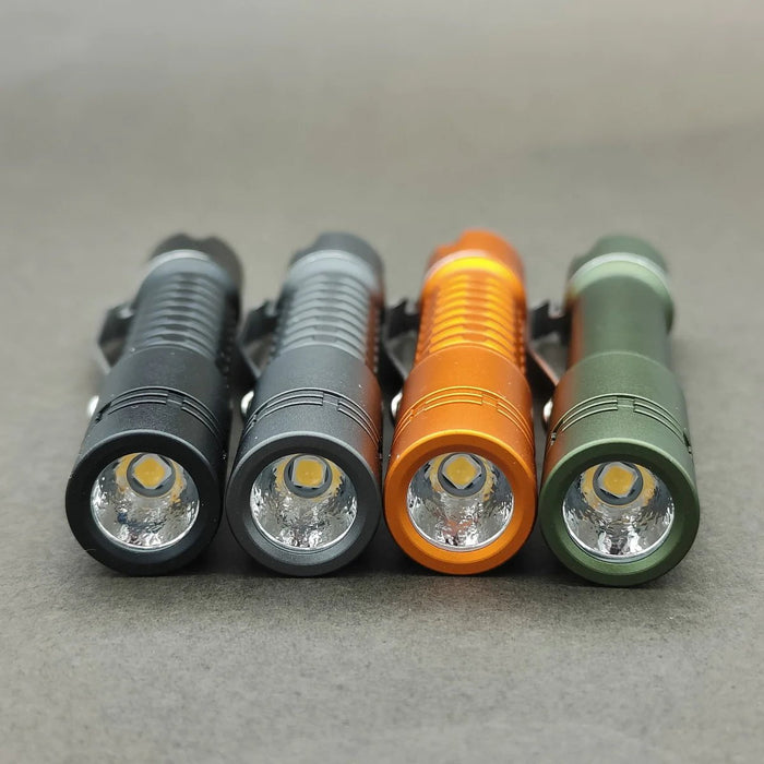 Four different colored led flashlights, including the ReyLight Pineapple Mini Aluminum, on a gray surface. The flashlights are powered by AAA batteries.