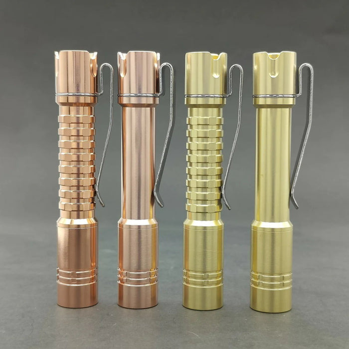 Four metal tactical flashlights, including the ReyLight Pineapple Mini Brass, standing upright on a grey background.