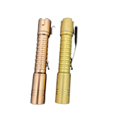 Two different colored ReyLight Pineapple Mini Copper flashlights on a black surface.