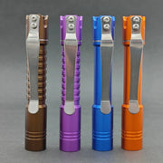 Four flashlights in brown, purple, blue, and orange stand vertically against a gray background, each with a metal clip. Among them is the sleek ReyLight Pineapple Mini MK II - Aluminum featuring the efficient Nichia 519a LED for enhanced illumination.