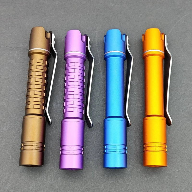Four ReyLight Pineapple Mini MK II flashlights in brown, purple, blue, and orange with pocket clips are lined up on a gray background. They feature advanced Nichia 519a LEDs for superior illumination.