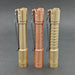 Three metal flashlights, including the stylish ReyLight Pineapple Mini MK II in copper and brass, stand upright on a gray surface. Their distinct textures range from smooth to engraved and ribbed, with gold-tone and copper-tone finishes. Each features a rechargeable 10440 battery and Nichia 519a LED for top performance.