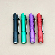 Four ReyLight Pineapple Mini MK3-Aluminum flashlights in black, green, purple, and red with Nichia 519a LEDs are lined up on a tan surface. Each runs on a rechargeable 10440 battery.