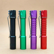 Four ReyLight Pineapple Mini MK3-Aluminum flashlights in black, green, purple, and red stand upright on a beige background, each featuring a rechargeable 10440 battery and a bright Nichia 519a LED.