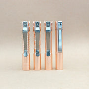 Four ReyLight Pineapple Mini MK3 - Copper&Brass pens with silver clips stand upright in a row against a plain beige background. Each pen features a distinctively textured grip inspired by the intricate patterns commonly seen on premium EDC flashlight bodies.