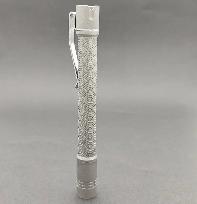 A ReyLight Pineapple Mini Penlight with a metal handle on a gray surface.