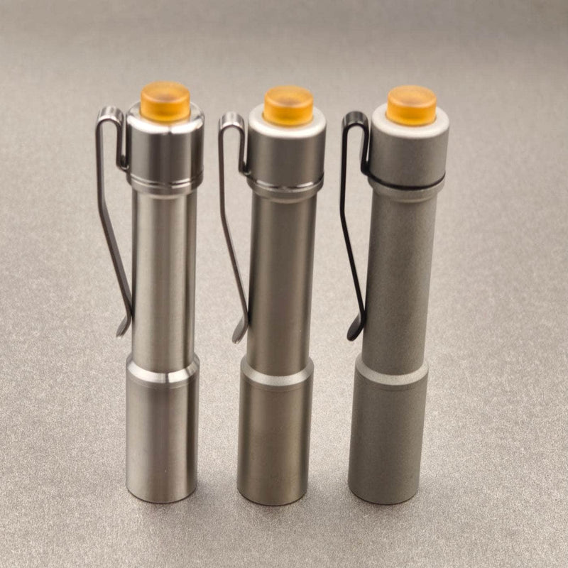 ReyLight Pineapple Mini stainless steel flashlights in Raw, Satin, and Stonewash finishes with amber PEI buttons