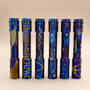 Six ReyLight Pineapple Mini Ti MK3 flashlights—hand carved and heat anodized—each with unique engravings, are displayed upright on a plain background.