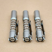 Three ReyLight Pineapple Mini Titanium MK3 - Krystal hexagonal pocket flashlights with clips are arranged side by side on a plain brown surface.