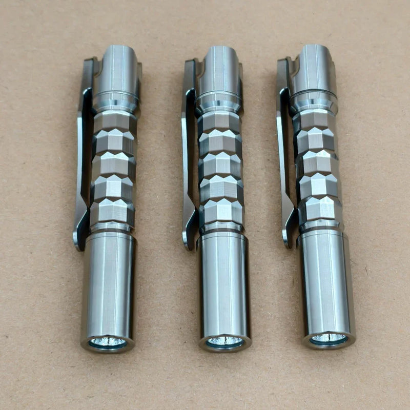 Three ReyLight Pineapple Mini Titanium MK3 - Krystal pens with hexagonal grips and clips are arranged side by side on a plain brown surface.