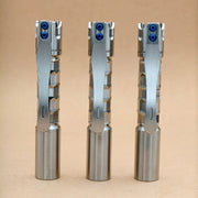 Three ReyLight Pineapple Mini Titanium MK3 - Krystal flashlights with hexagonal-patterned grips and pocket clips stand upright on a plain tan surface.