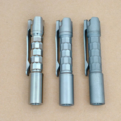 Three ReyLight Pineapple Mini Titanium MK3 - Krystal pens with hexagonal grips and pocket clips are arranged side by side on a plain brown surface.