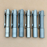 Six ReyLight Pineapple Mini Titanium - MK3 pen-style flashlights, perfect for everyday carry, are lined up on a brown surface; three have grooved grips and three have smooth bodies, all featuring convenient pocket clips.