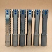 Six ReyLight Pineapple Mini Titanium - MK3 bolt-action pens with blue screws stand upright in a row against a plain brown background, perfect for everyday carry.