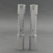 Two ReyLight Pineapple Mini Titanium - MK3 EDC flashlights with patterned grips stand upright on a gray surface against a gray background.