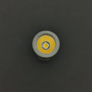 Close-up, top view of the ReyLight Pineapple Mini Titanium - MK3’s high-CRI LED bulb with a metallic ring and yellow circular reflector—perfect for an everyday carry titanium flashlight—set against a dark background.