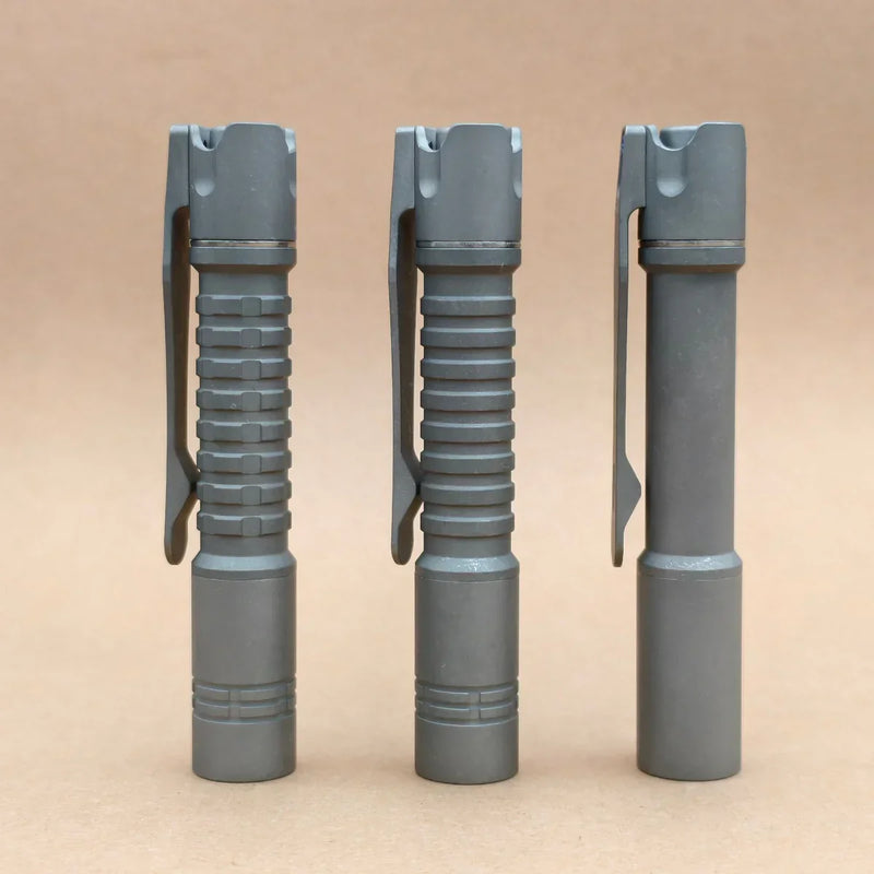 Three ReyLight Pineapple Mini Titanium - MK3 flashlights with pocket clips, ideal for everyday carry, stand upright in a row against a plain beige background.