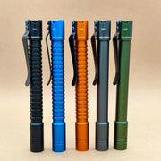 Five metal pen-shaped flashlights, including a rechargeable ReyLight Pineapple Penlight-MK II-Aluminum and a high-CRI LED flashlight, in black, blue, orange, gray, and green stand upright side by side on a light brown background.