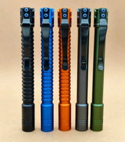 Five ReyLight Pineapple Penlight-MK II-Aluminum models in black, blue, orange, grey, and green stand upright on a neutral background—each a sleek rechargeable penlight with high-CRI LED for vivid illumination.