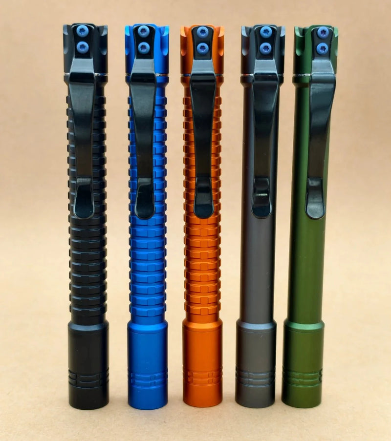 Five ReyLight Pineapple Penlight-MK II-Aluminum models in black, blue, orange, grey, and green stand upright on a neutral background—each a sleek rechargeable penlight with high-CRI LED for vivid illumination.