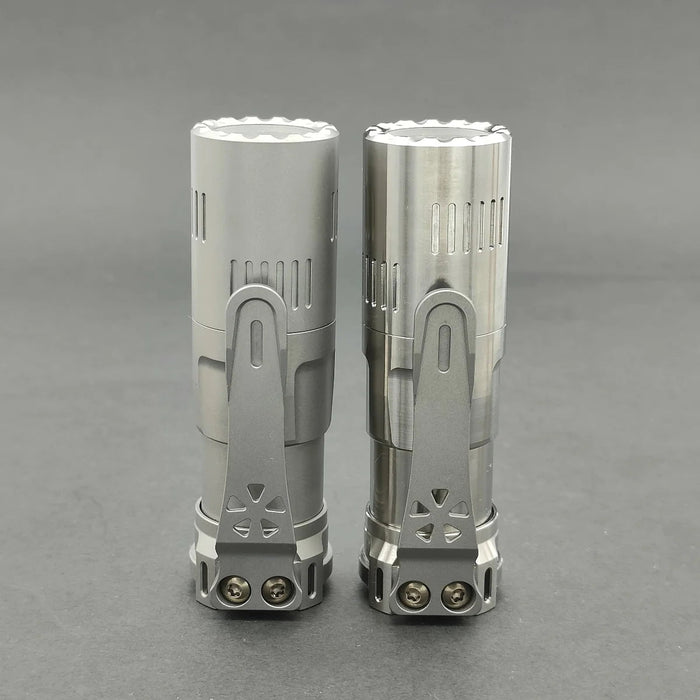 A pair of Reylight Rook - Ti flashlights on a gray surface.