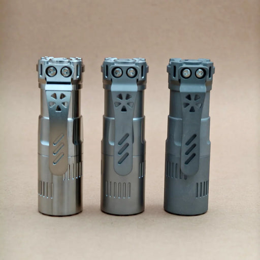 Three ReyLight Rook - Ti flashlights with dual LED bulbs and 18350 battery support stand upright on a plain, light brown surface against a matching background.
