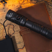 The Weltool F9R rechargeable LED flashlight charges via USB-C, resting on a brown leather notebook placed on a vintage world map.