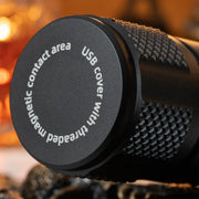 Close-up of the Weltool F9R, a cylindrical black rechargeable LED flashlight featuring a textured grip and a cap labeled "USB cover with threaded magnetic contact area.