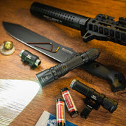 The Weltool LH20, a tactical 700-lumen flashlight, shines on a wooden surface next to a large knife, rifle part, batteries, aluminum reflector lens, and assorted gear.