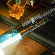 A Weltool LH20 tactical LEP weapon light mounted on a firearm emits a bright 700-lumen beam; a glass of amber liquid sits nearby on the table.